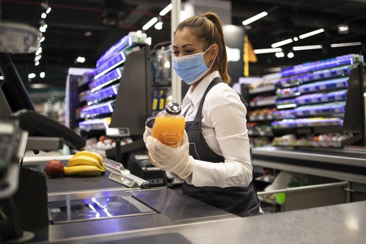 Cashier working in a supermarket with a mask on