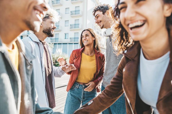 Happy multiracial friends having fun together walking on city street