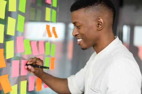 smiling man writing on post it notes on the wall