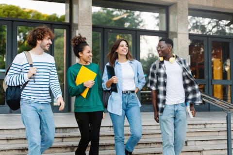 Multi ethnic group of Latin and African American college student friends walking outside University building