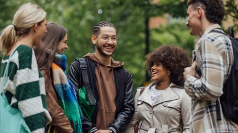 Diverse group of students chat together on campus